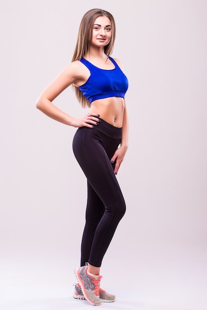 Free photo tough young woman standing on grey background. muscular female looking at camera. female bodybuilder wearing gloves ready for gym exercise.