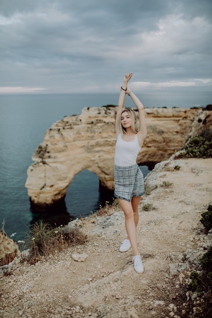 Free Photo tourism in portugal, europe. lifestyle blonde female tourist on sandstone rocks