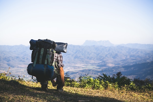 Free photo tourist  from mountain top. sun rays. man wear big backpack against sun light