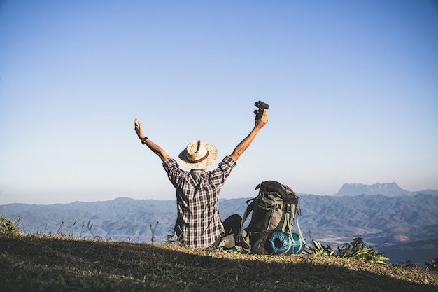 Tourist  from mountain top. sun rays. man wear big backpack against sun light