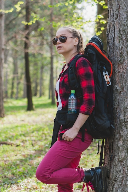 Free photo tourist girl leaning against a tree