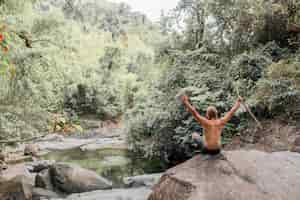 Free photo tourist sits on a stone in the forest. sumbawa