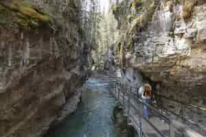 Free photo tourist walking on the wooden pathway in the johnston canyon captured in canada