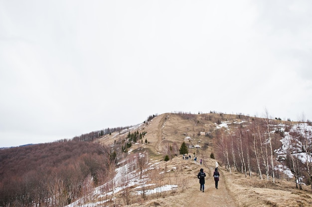 Tourists group hiking at snowy mountain valleys at Carpathian mountains View of Ukrainian Carpathians and Yaremche from the top of Makovitsa