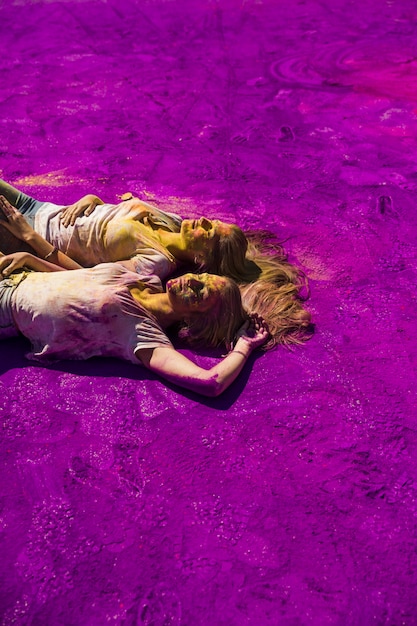 Free photo tow young woman relaxing on purple holi color