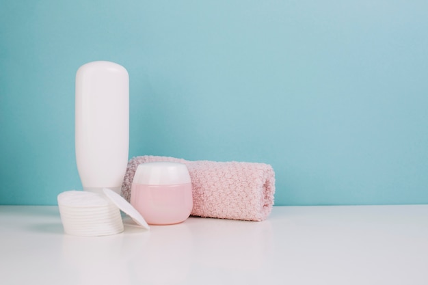 Towel and cotton pads near cosmetics bottle and jar