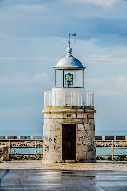 Tower in front of the water under a cloudy sky