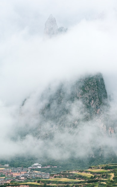 Town and a rocky mountain covered with fog