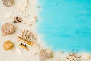 Free photo toy boat and seashells among sand on board