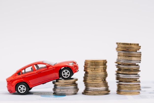 Free photo toy car going up on the increasing stack of coins against white background