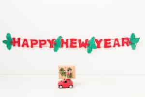 Free photo toy car with gift near happy new year inscription