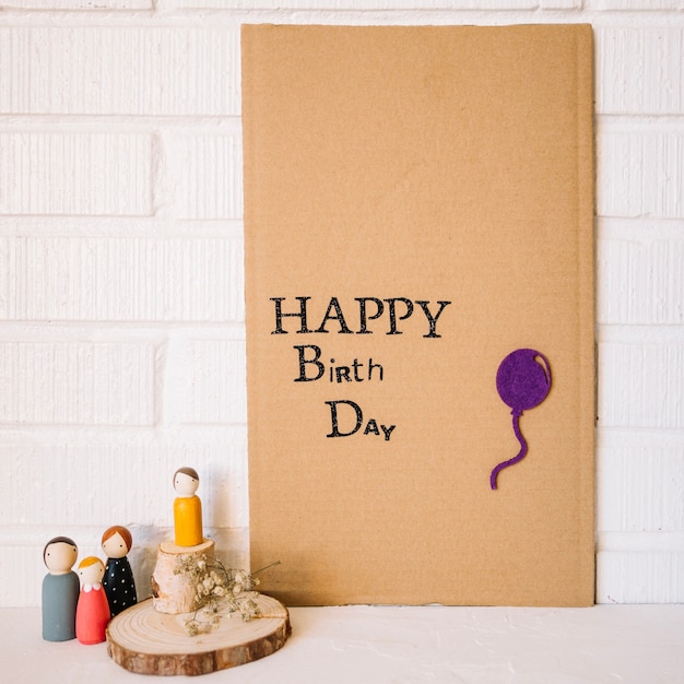 Toy family near cardboard with birthday greeting