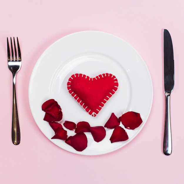 Free photo toy heart with flowers petals on plate