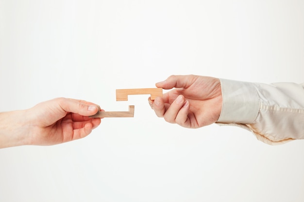 Free photo the toy wooden puzzle in hands solated on white background