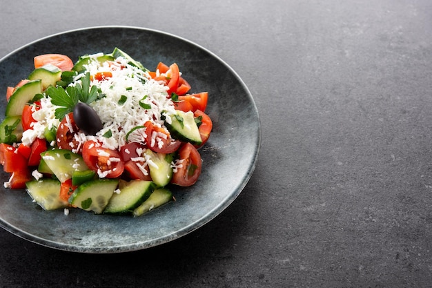 Traditional Bulgarian shopska salad with tomatocucumber and bulgarian sirene cheese on black background