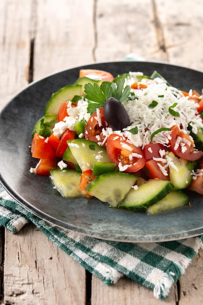 Traditional Bulgarian shopska salad with tomatocucumber and bulgarian sirene cheese on wooden table