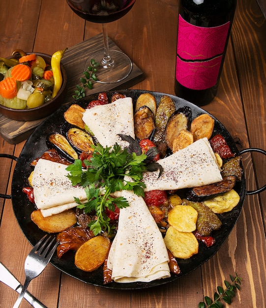 Traditional caucasian sac ici with fried chicken, eggplant, potatoes, tomatoes, zucchini and served with lavash, parsley, turshu. 