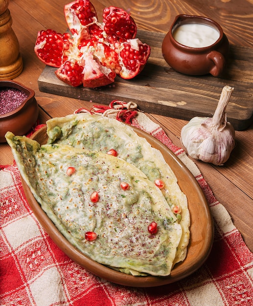 Traditional caucasian vegetable gutab, kutab, gozleme with sumakh, granate seeds and yogurt in wooden plate