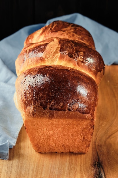 Traditional French brioche baked concept Fresh homemade organic brioche bun on rustic table top view vertical frame Closeup selective focus