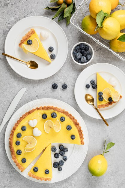 Traditional French lemon pie with blueberries on a white stone background