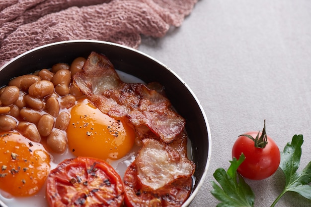 Free Photo traditional full english breakfast in cooking pan with fried eggs, bacon, beans, grilled tomatoes.