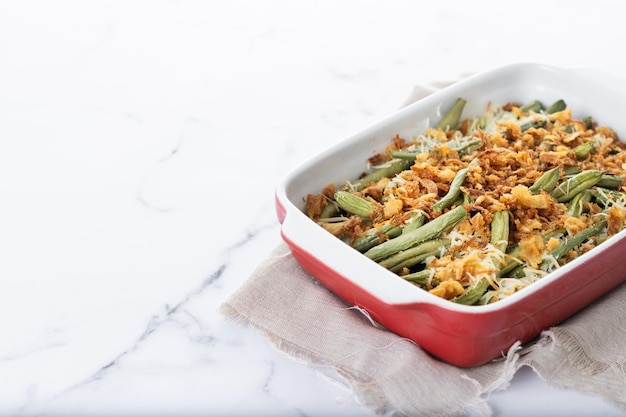 A traditional green bean casserole topped with French Fried Onions and cream of mushroom isolated on white background Copy space