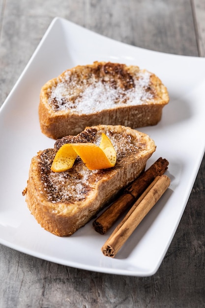 Free photo traditional homemade spanish torrijas decorated with cinnamon and orange peel on wooden table