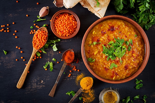 Traditional Indian soup lentils. Indian Dhal spicy curry in bowl, spices, herbs, rustic black wooden table