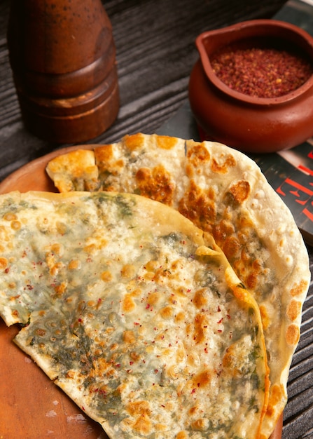 Traditional meat vegetable gutab, qutab, gozleme on wooden board with sumakh. 