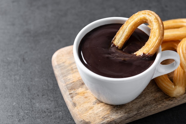 Traditional Spanish churros with hot chocolate on black slate background