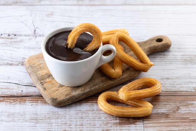 Traditional Spanish churros with hot chocolate breakfast on wooden table