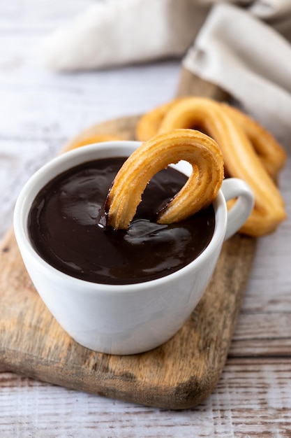 Traditional Spanish churros with hot chocolate breakfast on wooden table