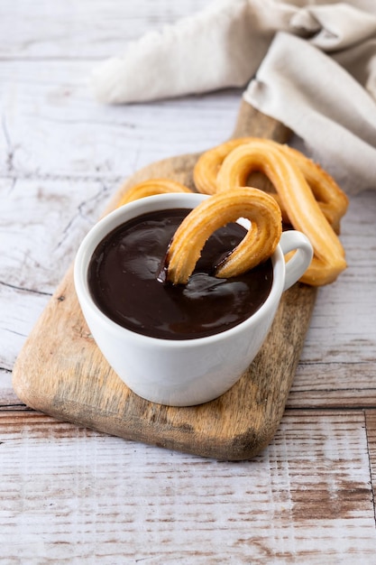 Traditional Spanish churros with hot chocolate breakfast on wooden table