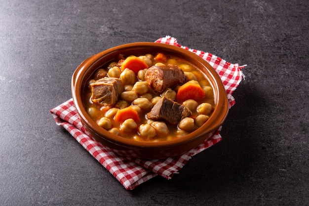 Traditional Spanish cocido madrileno in bowl on black background