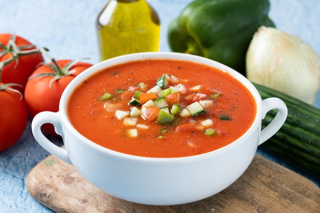 Traditional Spanish gazpacho soup in bowl on blue background