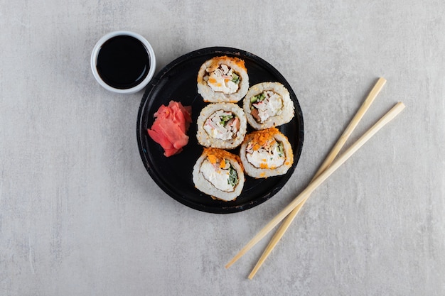 Traditional sushi rolls decorated with crispy chips on black plate. 