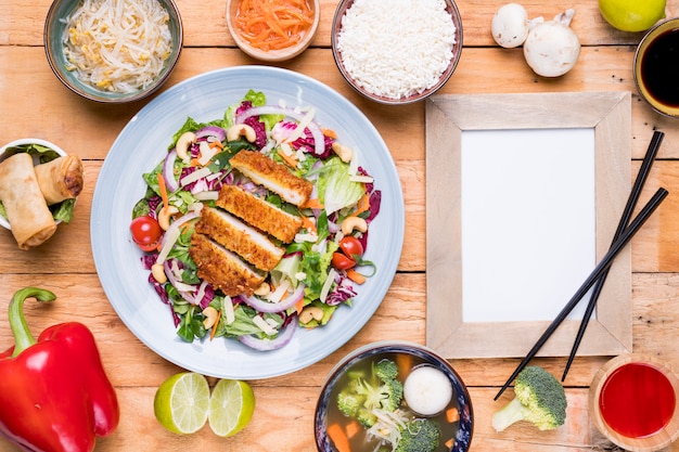 Traditional thai food with blank picture frame and chopsticks on wooden table