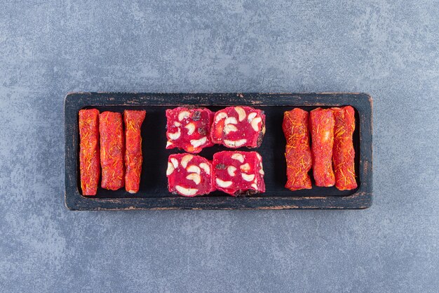 Traditional Turkish delights on a wooden plate on the marble surface