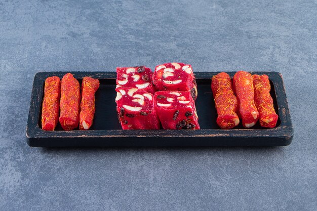 Traditional Turkish delights on a wooden plate on the marble surface