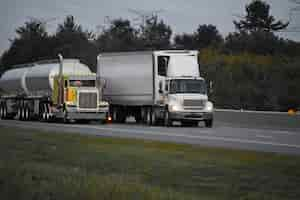 Free photo trailer trucks driving on the road surrounded by beautiful green trees