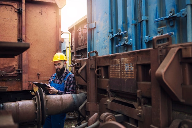 Train maintenance railroad worker checking wagons and cars before departure