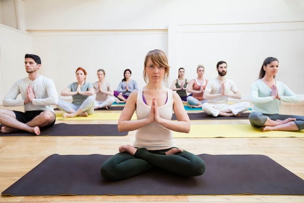 Free photo trainer assisting group of people with lotus position