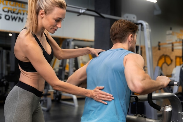 Trainer helping beginner at the gym