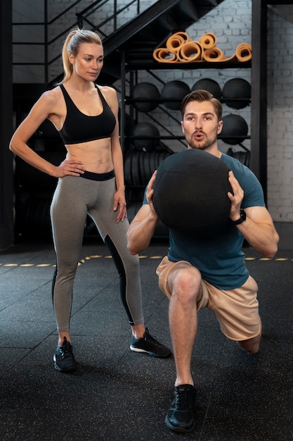 Free photo trainer helping beginner at the gym