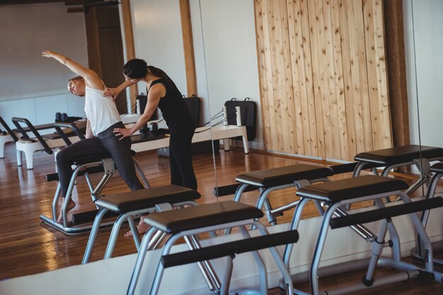 Trainer helping a woman while practicing pilates