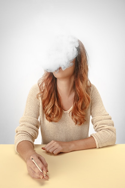 Tranquil woman sitting and smoking resting at the table.