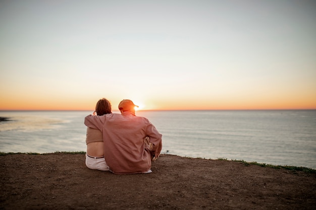 Free photo trans couple watching the sunset on the beach