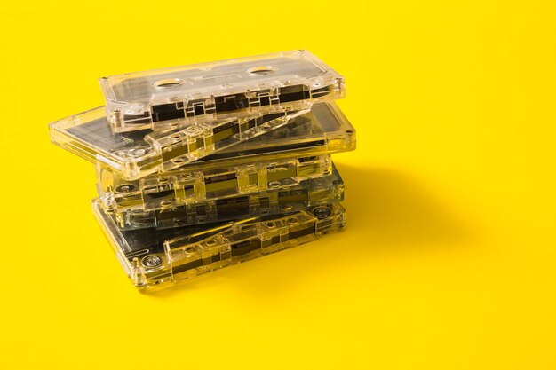 Transparent audio cassette tapes stack on yellow background