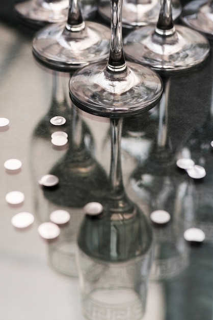 Transparent glasses and silver confetti over reflective desk