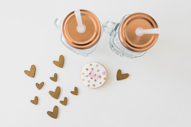 Free photo transparent mason jar with love cookie and heart shapes on white backdrop